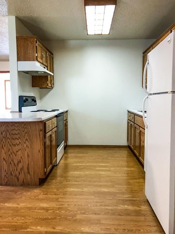 Dell Rapids apartment for rent - A kitchen with wooden cabinets and a white refrigerator.