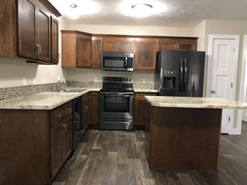 Dell Rapids apartment for rent - A kitchen with dark wood cabinets and black appliances.