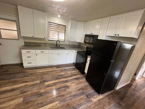 Hilo apartment for rent - a kitchen with white cabinets and a black refrigerator