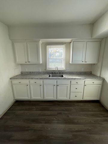 Lima house for rent - an empty kitchen with white cabinets and a sink
