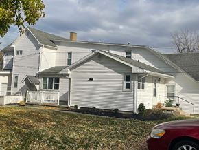 Cridersville apartment for rent - A white house with a red car parked in front.