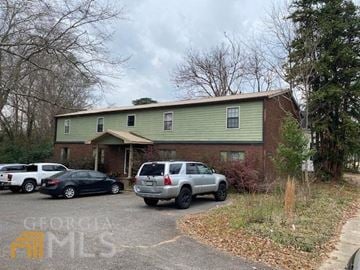 Milledgeville apartment for rent - a green house with cars parked in a parking lot