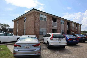 Houma apartment for rent - an apartment building with a parking lot full of cars