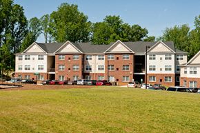 Orange apartment for rent - A large red brick building with a parking lot in front.
