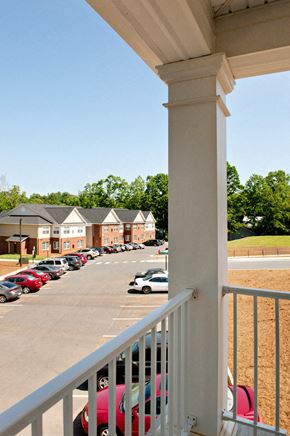 Orange apartment for rent - A white railing overlooks a parking lot.