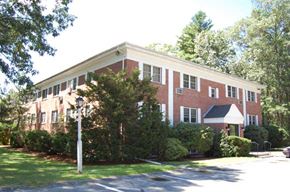 Tyngsborough apartment for rent - a brick building with trees and bushes in front of it