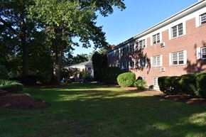 Tyngsborough apartment for rent - a view of the side of a brick building with grass and trees