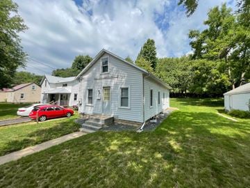 Menomonie house for rent - A white house with a red car parked in front.
