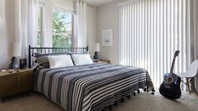 Austin apartment for rent - A bedroom with striped bedding and a guitar.