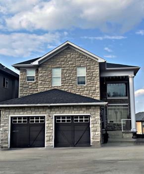 Calgary house for rent - a stone house with two garage doors in front of it