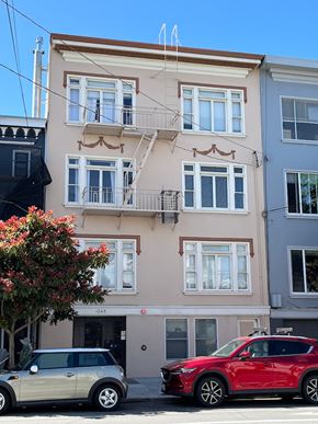 San Francisco apartment for rent - A red car is parked in front of a two-story building with a balcony.