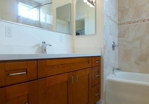 San Francisco apartment for rent - A bathroom with a white tub and wooden cabinets.