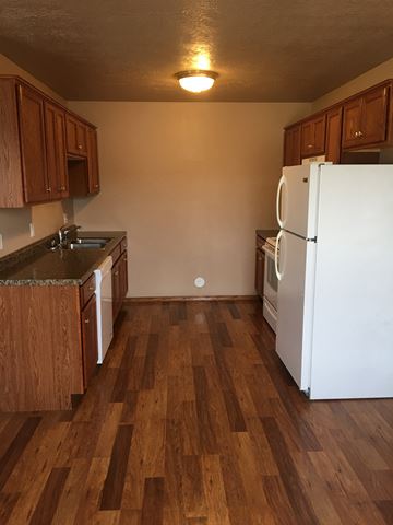 Dell Rapids apartment for rent - A kitchen with wooden floors and white appliances.