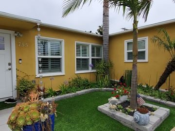 Imperial Beach house for rent - a yellow house with a yard and palm tree in front of it