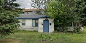 Anchorage apartment for rent - A small house with a blue door and windows surrounded by trees.