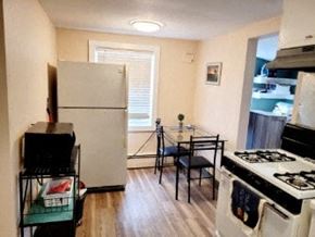 Anchorage apartment for rent - A kitchen with a white fridge, black stove, and a small table with two chairs.