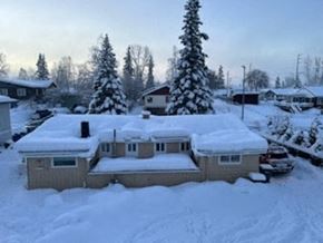 Anchorage apartment for rent - A house covered in snow with trees in the background.