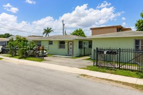 Miami apartment for rent - A street view of a residential area with houses and a fence.