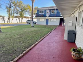 Pasadena apartment for rent - A red pathway leads to a white building with a blue balcony.