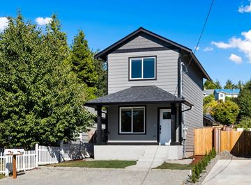 Tacoma apartment for rent - A grey house with a white fence in front.