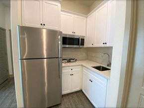 Merced house for rent - a kitchen with white cabinets and a stainless steel refrigerator