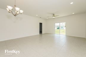Kissimmee house for rent - A spacious room with a chandelier and a ceiling fan.