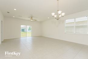 Kissimmee house for rent - A spacious room with a chandelier and a ceiling fan.