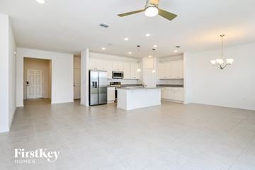 Kissimmee house for rent - a large white kitchen with white cabinets and a stainless steel refrigerator
