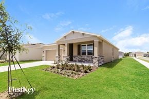 Bartow house for rent - a beige house with a lawn and a driveway
