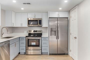 Phoenix house for rent - a kitchen with stainless steel appliances and white cabinets