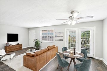 Brunswick apartment for rent - A living room with a brown couch, a television, and a dining table with chairs.