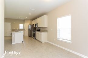 Yulee house for rent - a kitchen with white cabinets and appliances and a large window