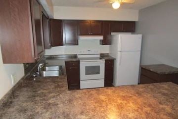 Lima apartment for rent - A kitchen with brown cabinets and a granite countertop.