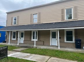 Akron apartment for rent - A two-story building with a porch and a sign that says "FOR RENT" in front of it.