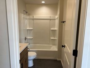 Shawnee house for rent - A white toilet is in a small bathroom with a walk-in shower.