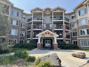 Edmonton apartment for rent - an exterior view of an apartment building with a walkway and a rock in front