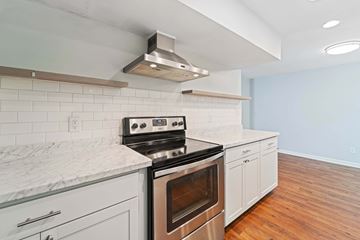 Jacksonville house for rent - A modern kitchen with a stove top oven and white cabinets.
