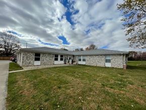 Cridersville apartment for rent - a stone house with a green lawn and a cloudy sky