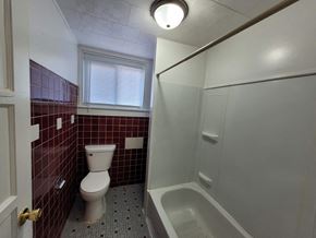 Lima apartment for rent - A bathroom with a toilet, tub, and window.