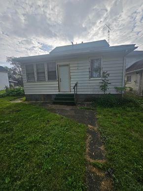 Lima house for rent - A small house with a white door and a small window is surrounded by a grassy area.