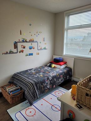 Vancouver apartment for rent - A child's bedroom with a bed, a basket, and a rug with circles on it.