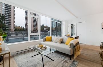 Coquitlam apartment for rent - A modern living room with a grey couch and a glass coffee table.
