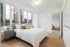 Coquitlam apartment for rent - A bedroom with a large bed and a view of a city skyline.