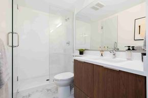 Coquitlam apartment for rent - A white toilet sits in a bathroom with a marble floor and a white sink.