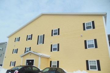 Charlottetown apartment for rent - A yellow house with black shutters and a white door.
