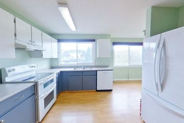 Fort Mcmurray house for rent - an empty kitchen with white appliances and blue cabinets