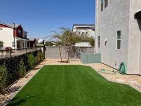 Goodyear house for rent - a backyard with a green lawn next to a house