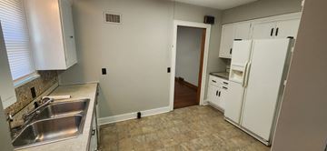 Lima house for rent - a kitchen with white cabinets and a sink and a refrigerator
