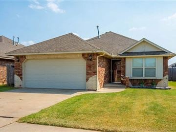 Yukon house for rent - a brick house with a garage and a lawn