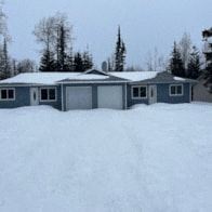 Kenai apartment for rent - A house with a garage is surrounded by snow.
